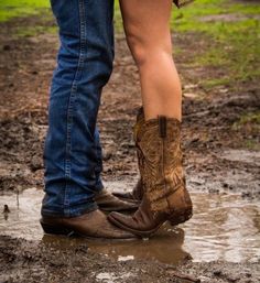 two people standing in the mud wearing cowboy boots