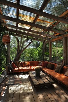 an outdoor living area with couches, tables and plants on the deck in the shade