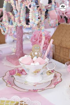 a teacup filled with candy and marshmallows next to a small tree