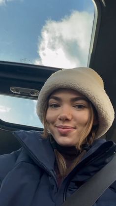 a woman sitting in the back seat of a car wearing a winter coat and hat