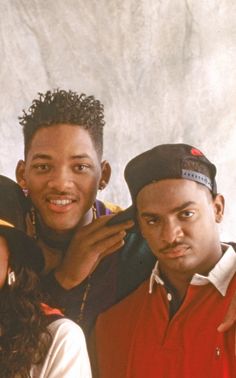 a group of people standing next to each other in front of a white wall and smiling at the camera