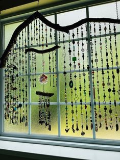 a window with beads hanging from it's side and a tree branch in the middle