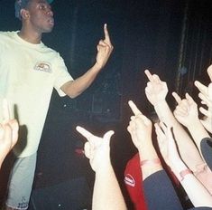 a man standing on top of a stage surrounded by lots of people holding their hands in the air