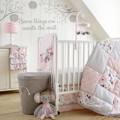 a white crib with pink and gray bedding