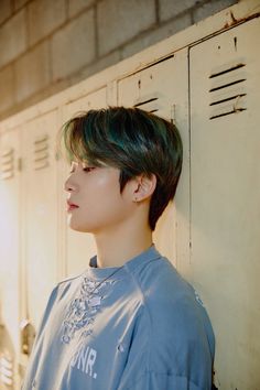 a young man with green hair standing in front of lockers