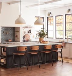 a kitchen island with stools in front of it and lights hanging from the ceiling