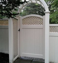 a white gate with a trellis on the top