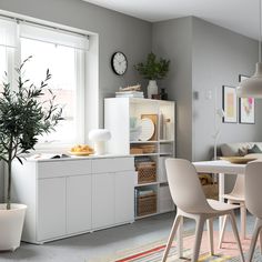 a white table and chairs in a room with a potted plant on the far wall