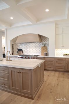 a large kitchen with an island in the middle and wood flooring on the other side