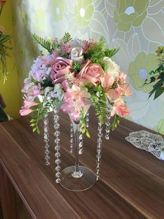 a vase filled with pink flowers on top of a wooden table next to a wall