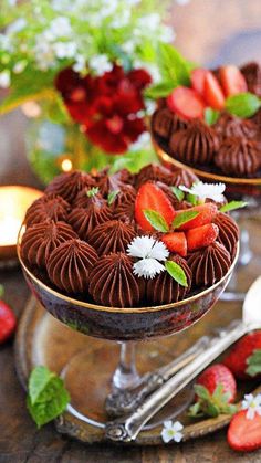 two desserts with chocolate frosting and strawberries in the middle on a table
