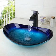 a blue glass bowl sink sitting on top of a counter next to a faucet