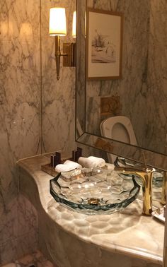 a fancy bathroom with marble counter tops and gold faucet lights on the wall