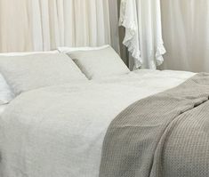 a bed with white sheets and pillows in a room