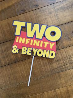 two infinity and beyond sign on wooden floor with lollipop stick sticking out