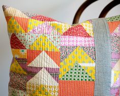 a colorful pillow sitting on top of a wooden chair