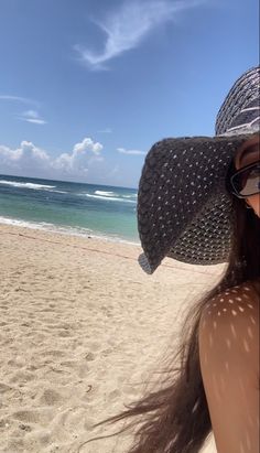 a woman wearing a hat and sunglasses on the beach