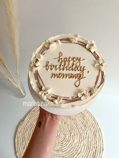 a hand holding a cake with the words happy birthday mommy written on it in frosting