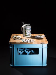 a beer can sitting on top of a blue cooler with plates and cups next to it