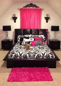 a black and white bed with pink rugs on the floor next to two nightstands