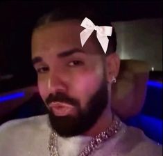 a man with a white bow tie on his head wearing a silver necklace and diamond choker