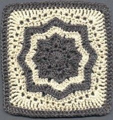a crocheted square with an intricate design on the center is shown in grey and white