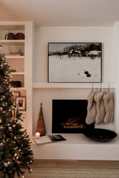 a decorated christmas tree in front of a fireplace with stockings hanging on the mantel