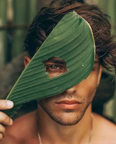 a man holding a large green leaf over his face