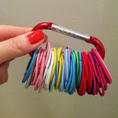 a person holding a red umbrella with many colored cords attached to it's handle