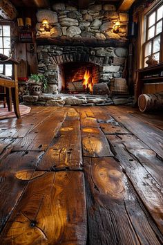 an empty room with wood floors and stone fireplace