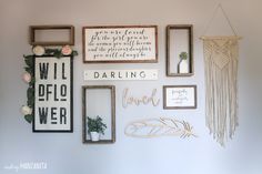 a wall filled with pictures and framed art on top of a white wall next to a potted plant