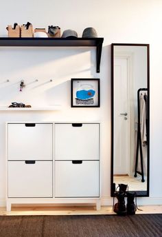 an image of a room with white drawers and black shelving unit on the wall
