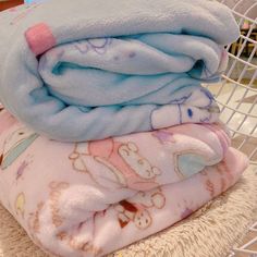 three baby blankets stacked on top of each other in a wire basket next to a stuffed animal