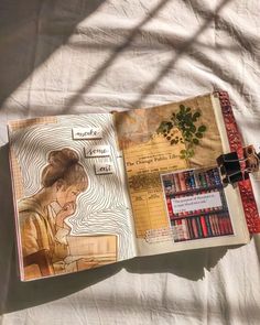 an open book sitting on top of a bed next to a white sheet covered ground