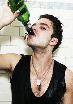 a man drinking from a green bottle in the shower