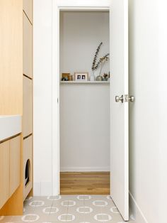 an open door leading into a white room with wooden cabinets and drawers on either side