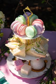 three tiered trays filled with sandwiches and macaroni and cheese on top of each other