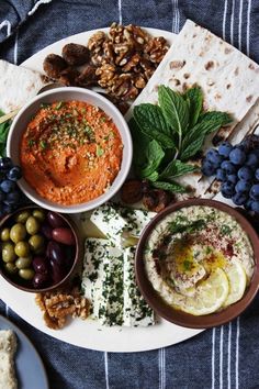 an assortment of food on a plate with crackers, olives, and pita bread