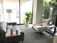 a living room filled with furniture next to a large glass wall window covered in greenery