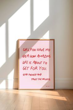 a pink sign sitting on top of a hard wood floor next to a white wall