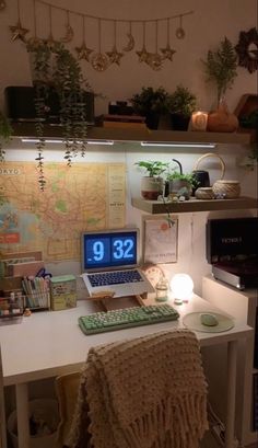 a laptop computer sitting on top of a white desk next to a plant filled wall