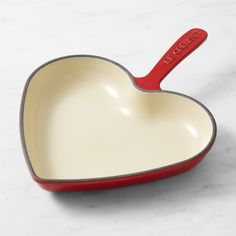 a heart shaped dish with a red handle