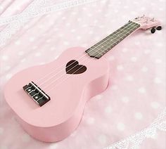 a pink ukulele is laying on a bed