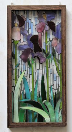 a stained glass window with purple flowers and green leaves in the center on a white wall