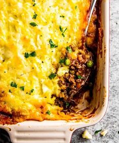 a casserole dish with meat, cheese and vegetables in it on a table