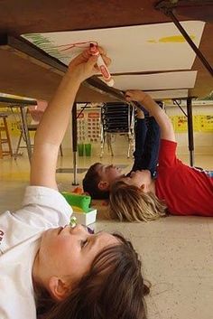 two people laying on the ground with their arms in the air and one person reaching for something