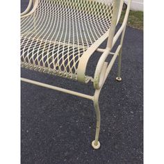 a white metal bench sitting on top of a street