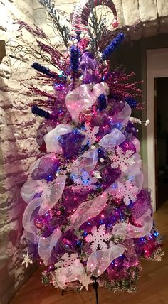 a christmas tree decorated with purple and white ribbons