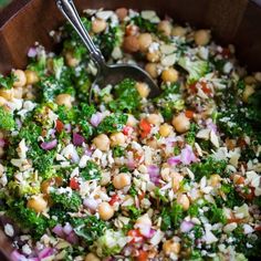 a wooden bowl filled with broccoli, chickpeas and red onion salad