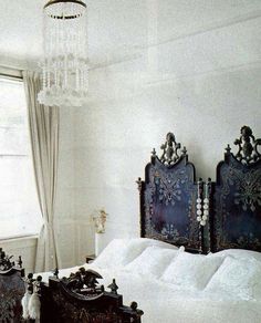 a bed with white sheets and black headboards in a bedroom next to a window